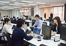 写真:デスクで会話する社員たち